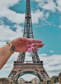 Low angle view of hand holding tower against cloudy sky