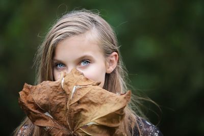 Close-up portrait of girl with dry leaf