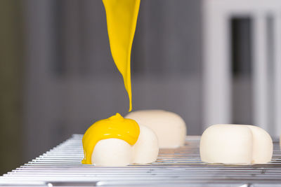 Close-up of cream over heart shape food on cooling rack