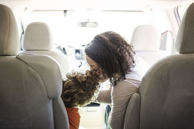 Mother kissing son on forehead in car