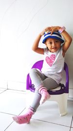 Portrait of cute girl sitting on tiled floor at home