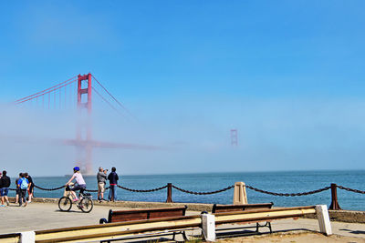 People at promenade against golden gate bridge during foggy weather