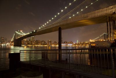 Illuminated bridge over river at night