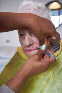 Elderly woman receiving facial hair removal from african american caregiver