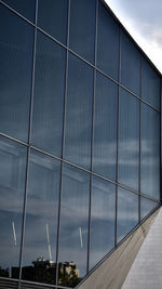 Low angle view of glass building against sky