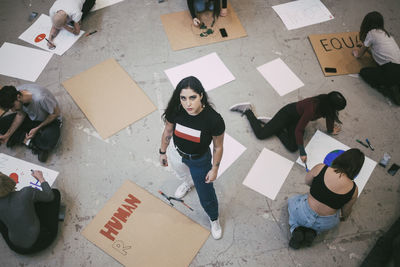 High angle portrait of woman standing while male and female activist preparing signboards in building