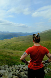 Rear view of woman standing on mountain against sky