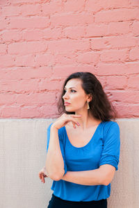 Thoughtful woman standing against wall