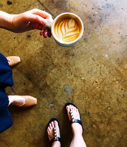 Low section view of  two people holding coffee cup