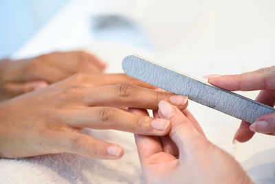 Beautician using filer on customer at nail salon