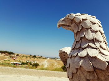 Close-up of eagle statue against clear blue sky on sunny day