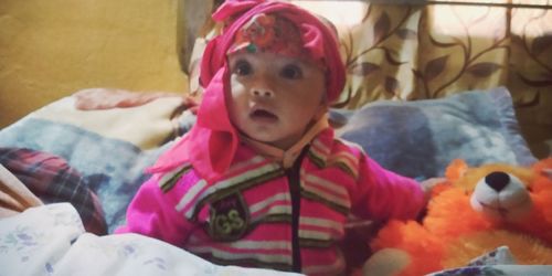 Portrait of cute baby girl with toy at home
