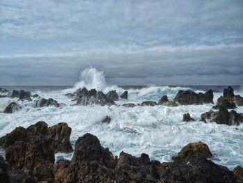 Scenic view of rocks in sea against sky