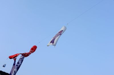 Low angle view of fishing kites hanging against clear sky