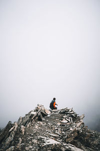 Men on rock in mountains against clear sky