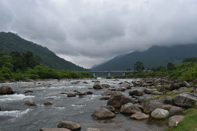 Rocks by river against sky