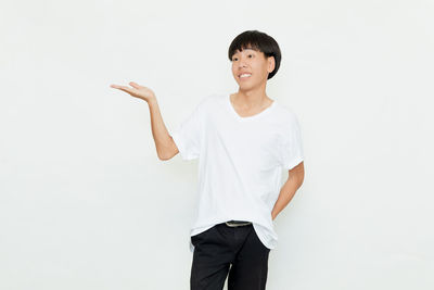 Portrait of young woman standing against white background