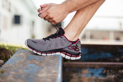 Low section of man tying shoelace outdoors