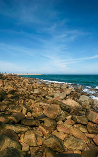 Rocks on beach against blue sky