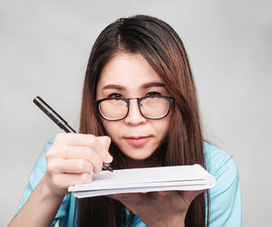 Portrait of young woman using smart phone against white background