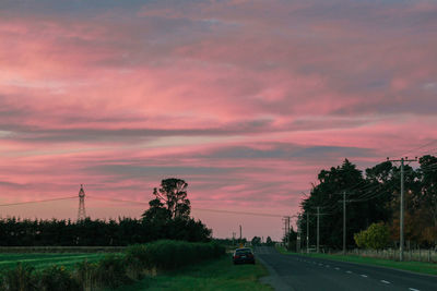 Cars on road against sky at sunset