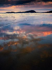 Scenic view of sea against dramatic sky during sunset