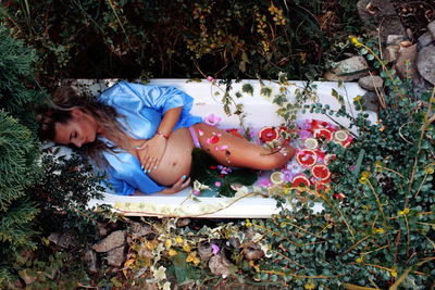 High angle view of pregnant woman lying in bathtub amidst plants