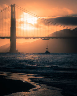 View of bridge over sea against cloudy sky during sunset