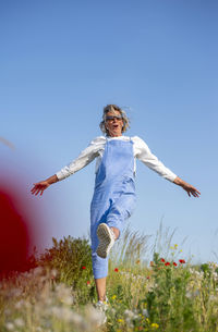 Full length of young woman jumping against clear sky