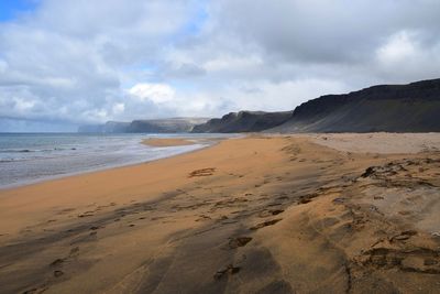 Scenic view of beach against cloudy sky