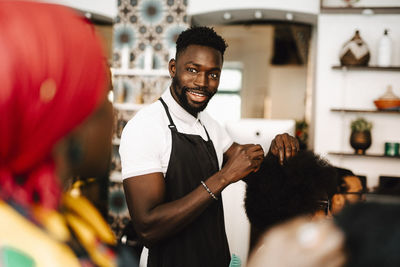 Smiling male hairdresser talking with female coworker in barber shop