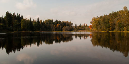 Panoramic view of lake by trees against sky during sunset