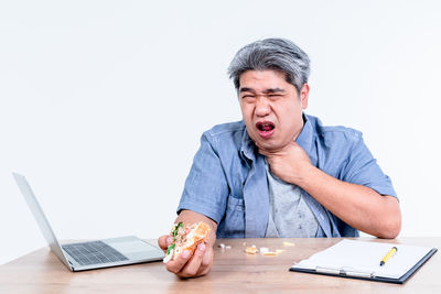 Young man using laptop on table against white background