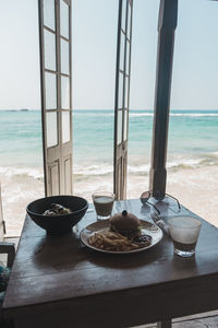 Lounge chairs and table at beach against sky