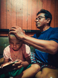 Father and daughter sitting on man looking at camera