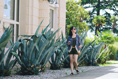 Portrait of young woman standing against plants