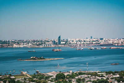 View of city at waterfront against blue sky