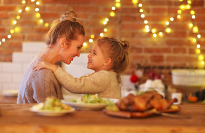 Side view of happy mother and daughter looking each other during celebration