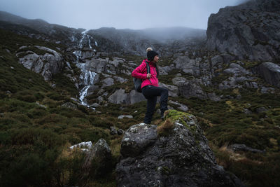 Rear view of man standing on rock against mountains