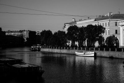 Boats in river by buildings in city against sky