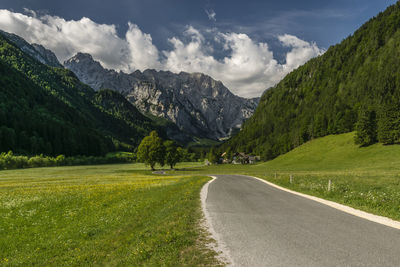 Road amidst green landscape and mountains against sky