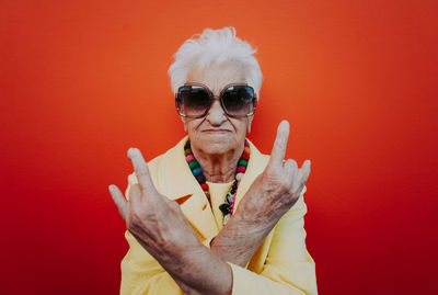 Portrait of senior woman gesturing against red background