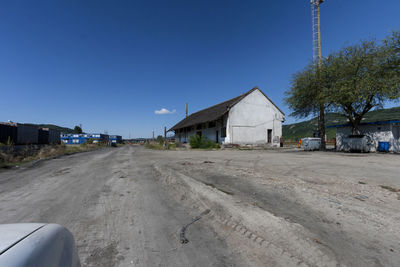 Road by building against clear blue sky