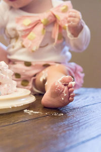 Baby eating cake with toes in cake