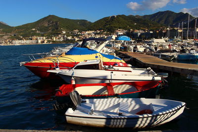 Boats moored at harbor against sky