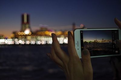 Man photographing through smart phone against sky