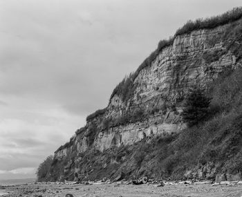 Rock formations on beach against sky