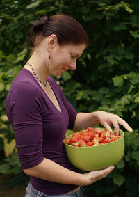 Side view of woman holding strawberries in bowl