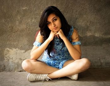 Portrait of woman sitting against wall