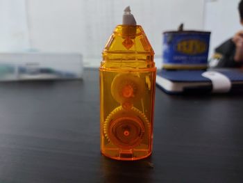 Close-up of yellow bottle with toy on table